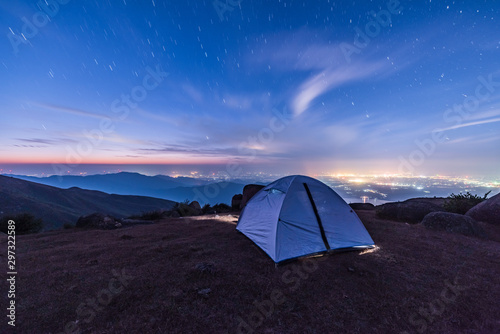 Tourist hikers tent in mountains at night with stars in the sky 