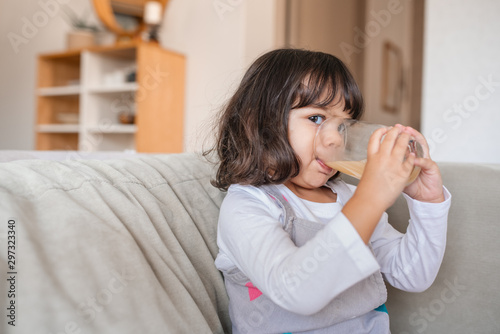 Cute little girl drinking juice at home