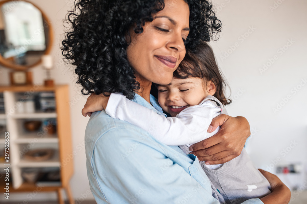 Mom and her cute little daughter hugging at home - obrazy, fototapety, plakaty 