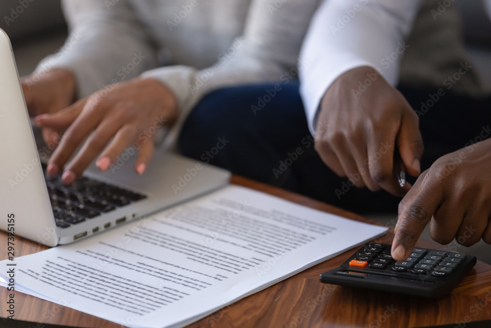 Close up of multiracial couple calculating finances paying online Close up of multiracial couple calculating finances paying online