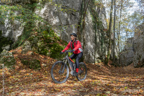 nice senior woman riding her electric mountain bike in the autumnal atmosphere in the Hells Holes of the Swabian Alb near the city of Urach, Baden Wuerttemberg, Germany © Uwe