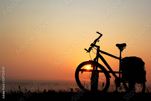 Silhouette of a bicycle against the orange sky at sunrise © aquatarkus