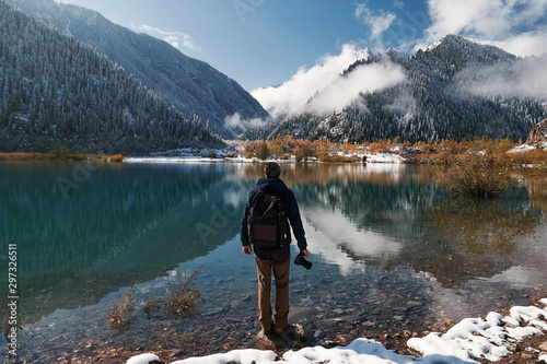 Fototapeta Naklejka Na Ścianę i Meble -  Travel photographer man with backpack at mountain lake Issyk, Almaty, Kazakhstan