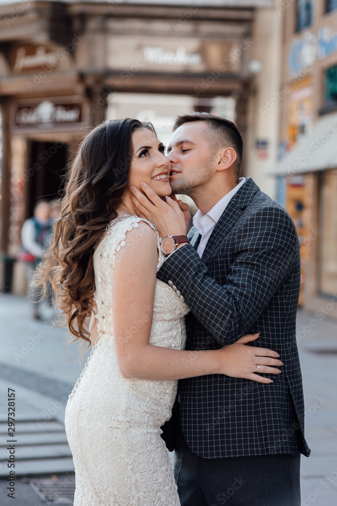 Love story of couple in the city. Love story. Portrait of a beautiful young couple in love standing and kissing. Handsome guy in suit and girl in white dress. Love story of couple in the city. Love story. Portrait of a beautiful young couple in love standing and kissing. Handsome guy in suit and girl in white dress.