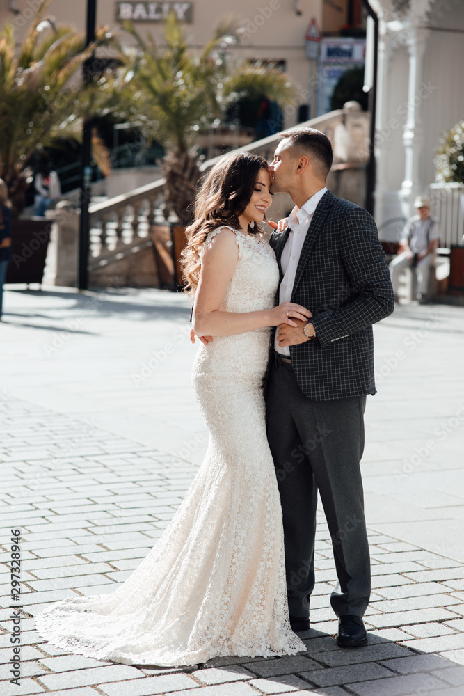 Happy couple in love on the background of buildings. Love story of couple in the city. Love story. Portrait of a beautiful young couple in love standing and kissing