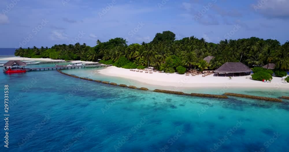 Aerial view panning down looking at a tropical island with a red boat docked off shore in the Maldives Aerial view panning down looking at a tropical island with a red boat docked off shore in the Maldives
