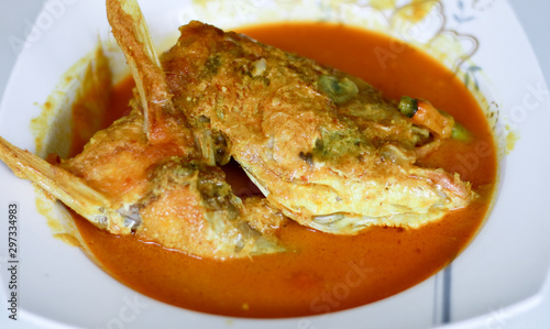 Snapper head gulai (curry) on white background. Gulai is type of food containing rich, spicy and succulent curry. photo