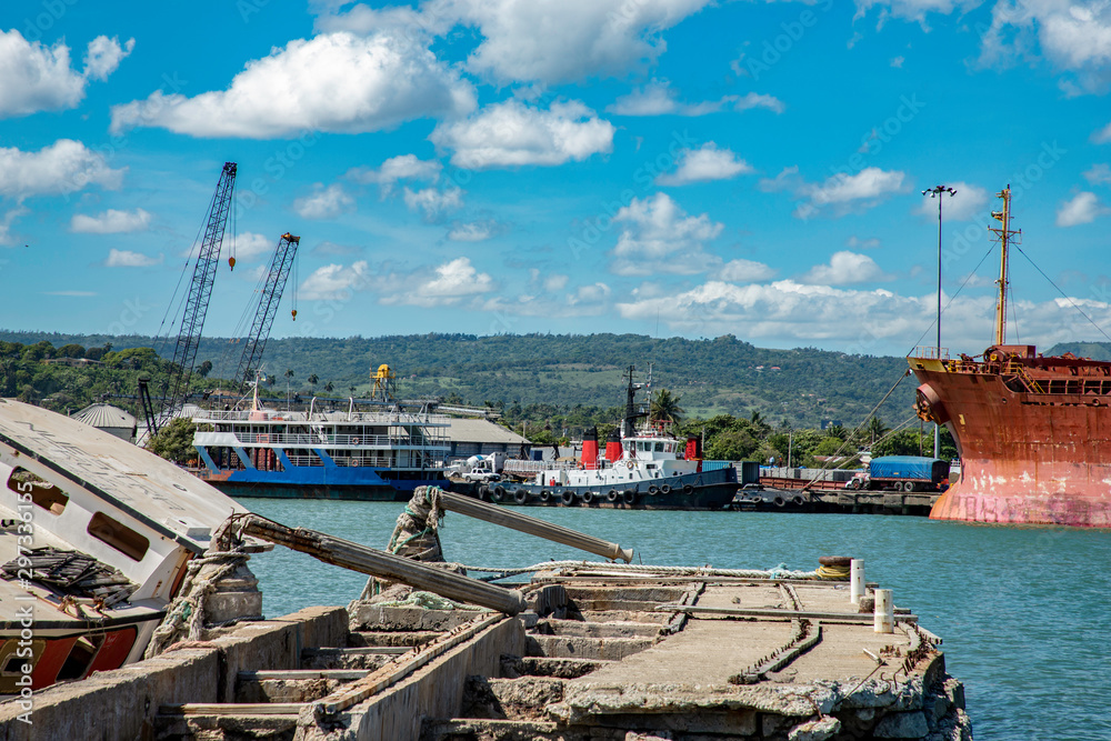 Old rusty ruined caribbean port before reconstruction, sunk ship, cranes, mountain view, Puerto Plata harbor, Dominican Republic