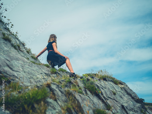 Young woman relaxing on rocky cliff by the sea