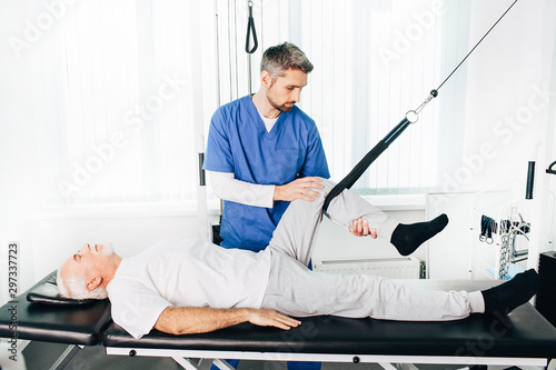 kinesiologist doing therapeutic exercises for an elderly patient. Kinesitherapy at the medical center