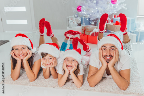 Merry Christmas and Happy New Year Happy family celebrating winter holiday at home. parents and children waiting for Christmas while lying near decorated New Year tree together