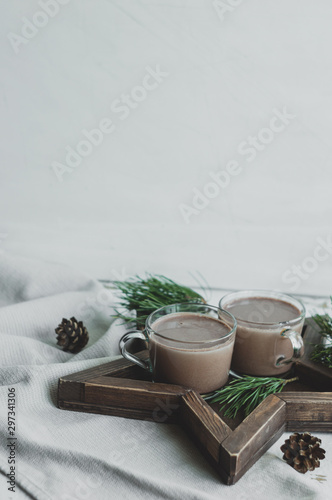 Star-shaped Wooden Tray with two cups of cocoa. Christmas decor with rustic style elements on a white background. Cones and pine branches New Year's decor.
