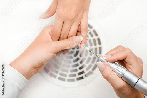 Bild auf Leinwand Woman use electric nail file drill in beauty salon