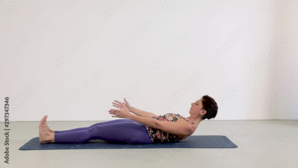 Attractive woman does yoga, she puts herself in the seated forward bend position. Attractive woman does yoga, she puts herself in the seated forward bend position.