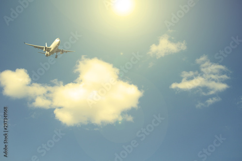 Airliner against the blue sky with white clouds. The sun shines.