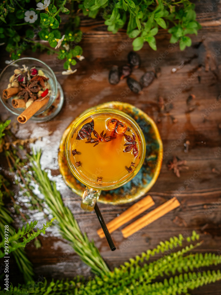 Hot mulled wine in a glass goblet with cinnamon sticks. Vegetation around Hot mulled wine in a glass goblet with cinnamon sticks. Vegetation around