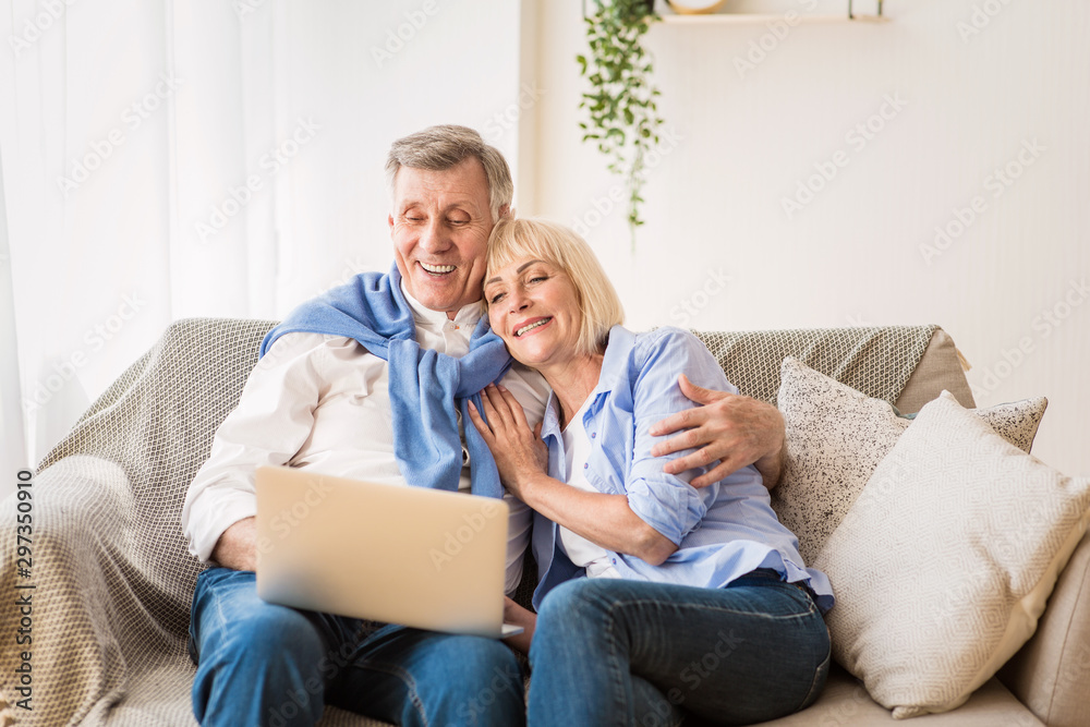 Mature man and his wife working with laptop at home