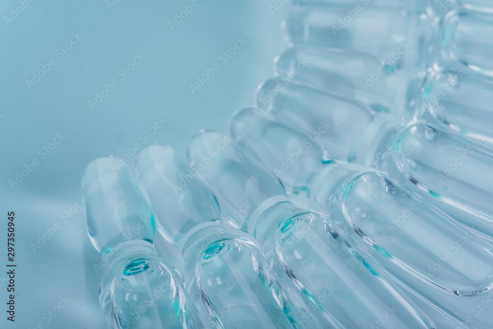 Glass medical ampoule vial for injection. Medicine is liquid sodium chloride with of aqueous solution in ampulla. Close up. Bottles ampule multicolor.