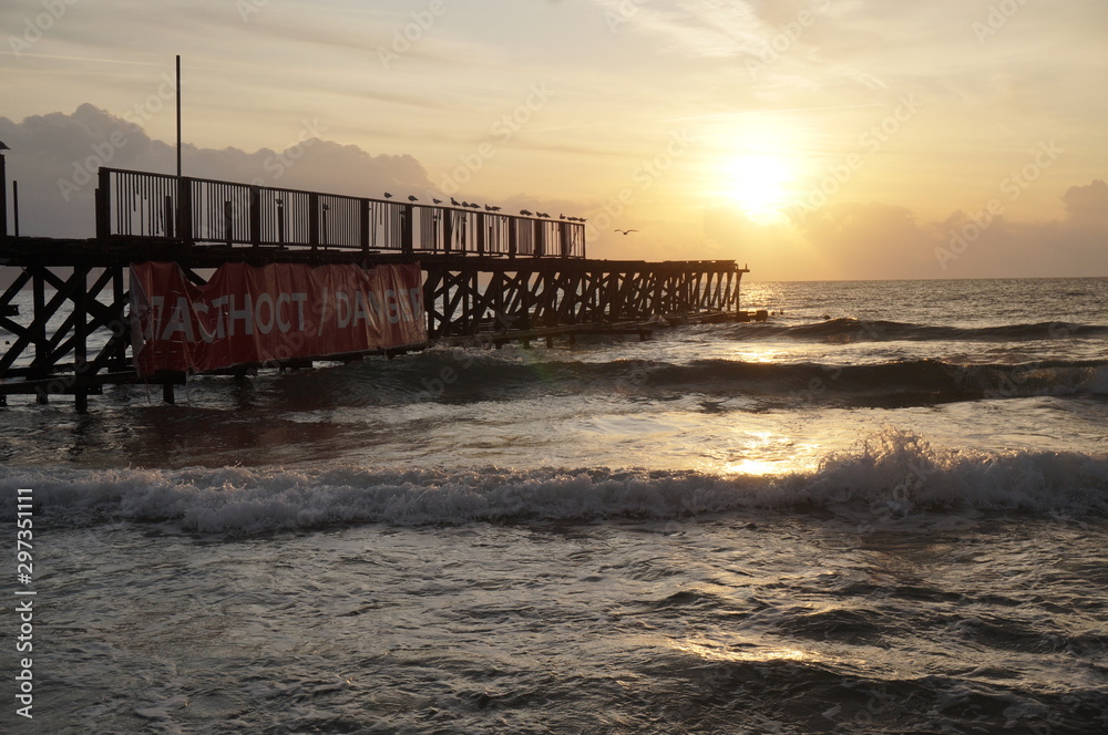 Obraz premium An old pier leaving in the sea leading to the rising sun in the morning, concept road leading to the light.