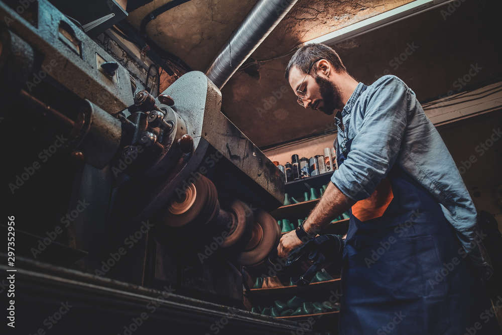 Bearded shoemaker in glasses is creating new pair of shoes using special machine. Bearded shoemaker in glasses is creating new pair of shoes using special machine.