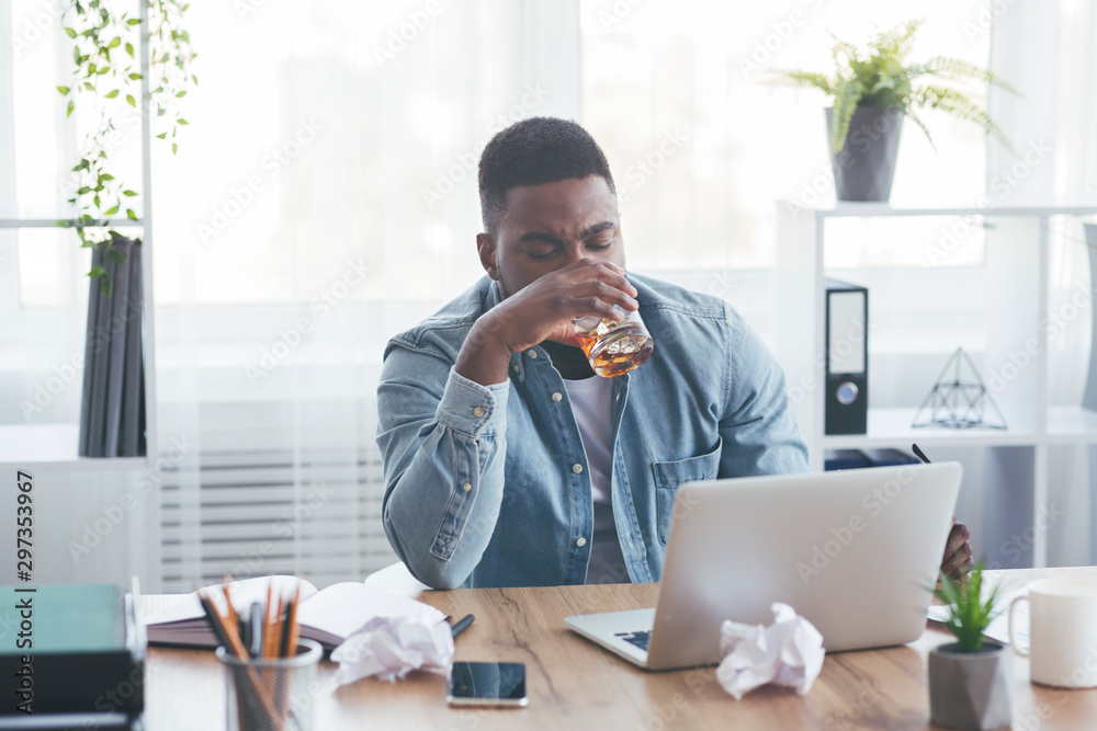 Tired african american employee drinking alcohol at workplace Tired african american employee drinking alcohol at workplace