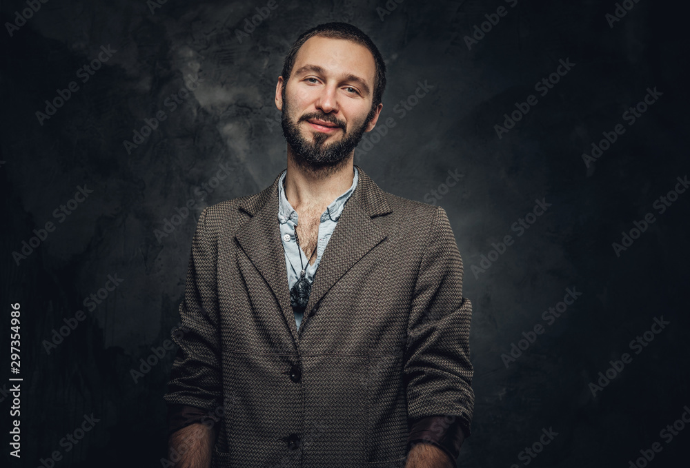 Happy smiling man with amulet on the neck is posing for photographer at dark photo studio.