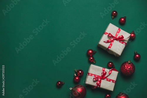 Creative composition with gifts or presents boxes with red bows, red balls on green background top view. Flat lay composition for birthday, christmas or wedding.