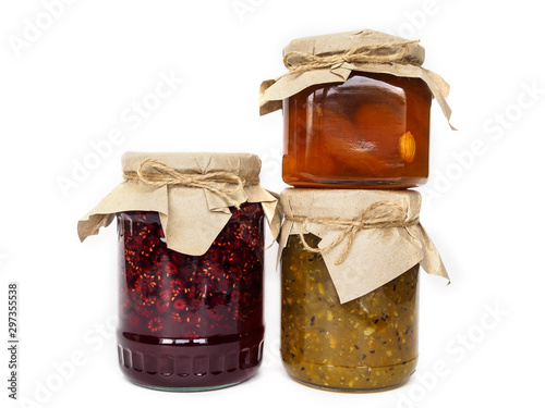 Three jars of jam on a white background. Apricot, raspberry and gooseberry jam. Jars of jam decorated with Kraft paper. White background