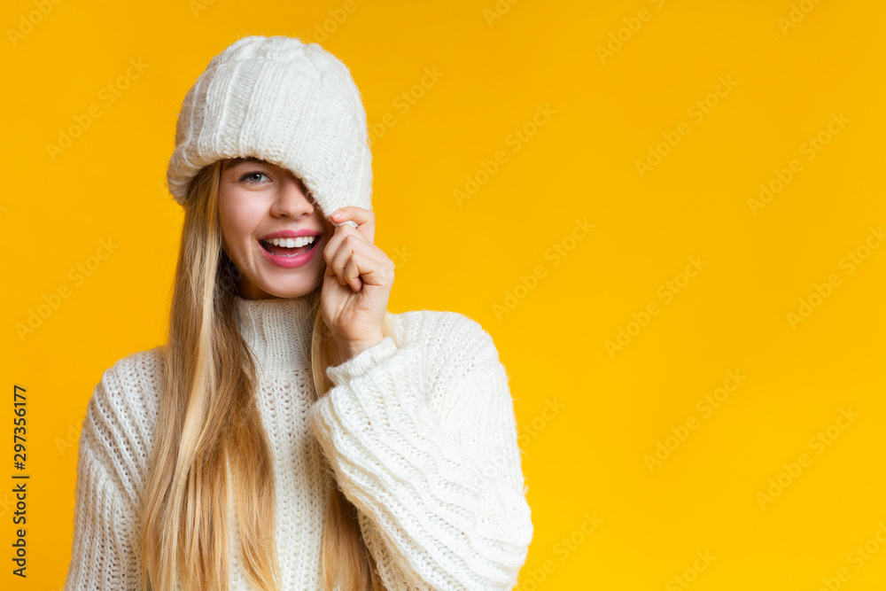 Playful girl covering her eye with knitted hat