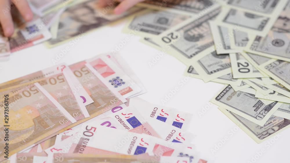 Kid sorting and counting money on table, close up. Child saving money. Euro and dollar banknotes on white desk Kid sorting and counting money on table, close up. Child saving money. Euro and dollar banknotes on white desk