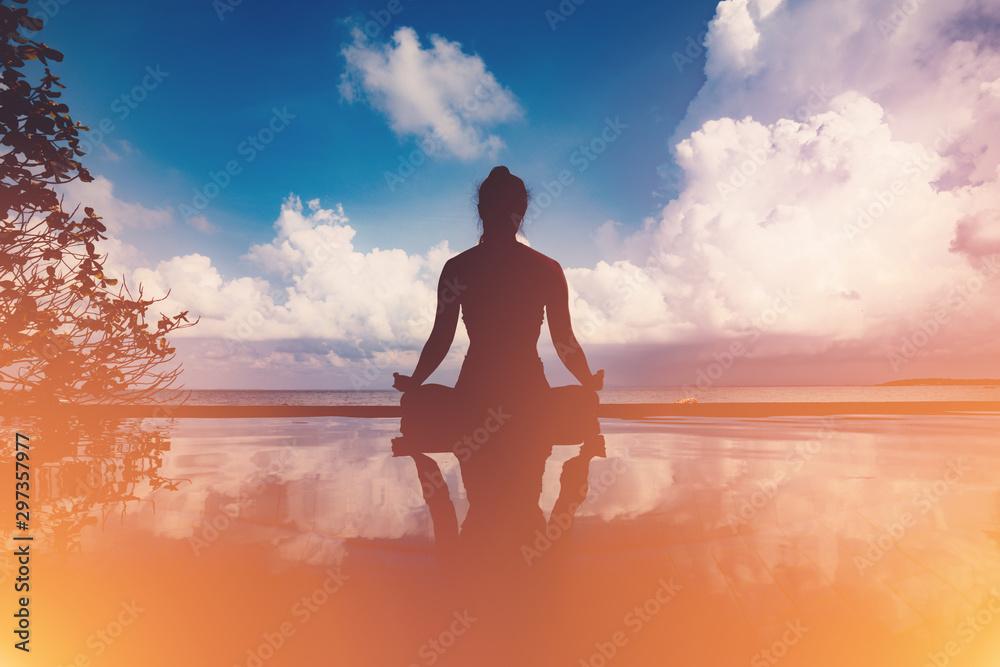 silhouette Athletic woman practice yoga lotus pose to meditation summer vacation on pier with sunset sea beach,Travel in tropical beach Thailand,vacations and relaxation Concept