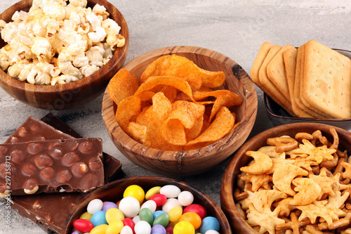Salty snacks. Pretzels, chips, crackers in wooden bowls and candy and chocolate on table
