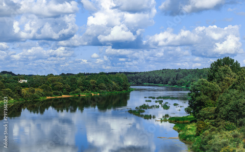 Summer landscape with river, cloudy sky, forest and sun