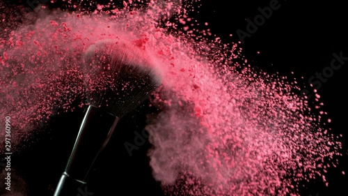 Super slow motion of makeup brush with falling pink powder, black background. Filmed on high speed cinema camera, 1000fps. photo