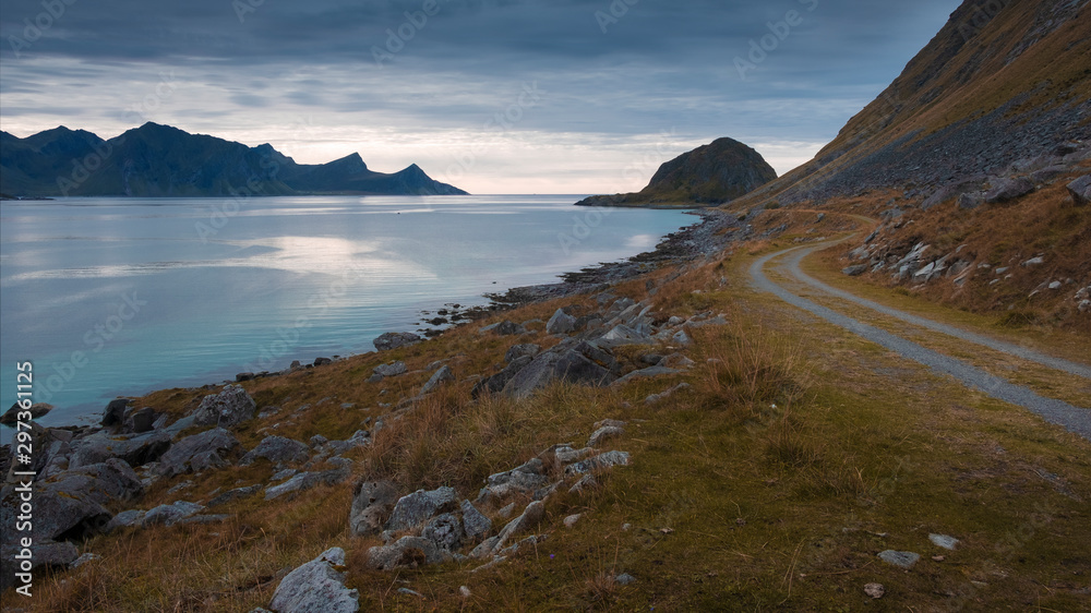 Evening landscape, winding dirt road along the sea from beach Haukland to Utakliev beach on the Lofoten Islands in polar Norway