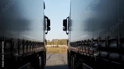 Two huge trucks are standing next to each other in loading hub, loaded with products, waiting for drivers to continue journey, deliver goods, deliver products, heavy truck parking, road transport
