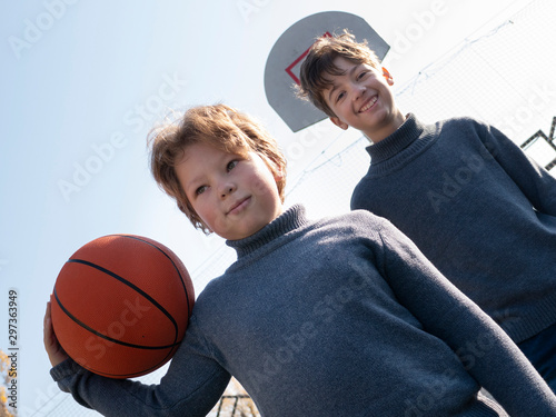 Two happy young boys playing basketball outdoors on a sports field © Chepko Danil