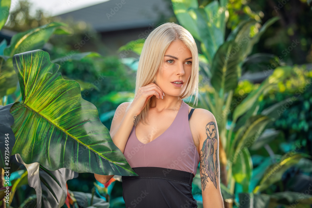 Fashion summertime portrait of sexy stunning sensual woman, posing at luxury hotel near jungle plants, wearing sport wear Fashion summertime portrait of sexy stunning sensual woman, posing at luxury hotel near jungle plants, wearing sport wear