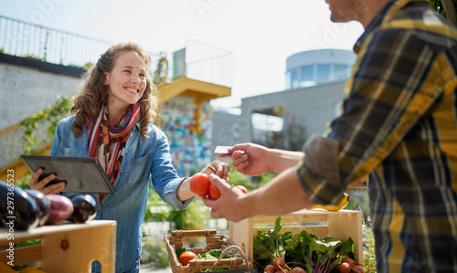 Friendly woman tending an organic vegetable stall at a farmer's photo