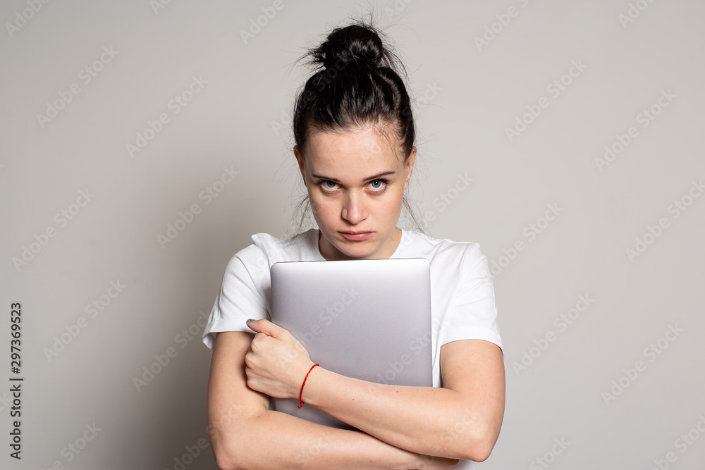 Upset female student holding a laptop and looking sternly at the camera. Upset female student holding a laptop and looking sternly at the camera.