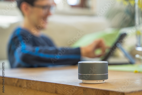 Smart ai speaker with child playing on tablet in the backround.  Smart home concept