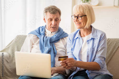 Mature couple shopping online in Internet, using laptop