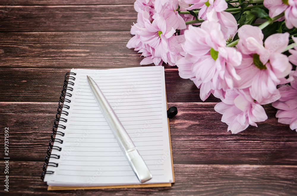Naklejka premium notebook and bouquet of beautiful flowers on a wooden background.