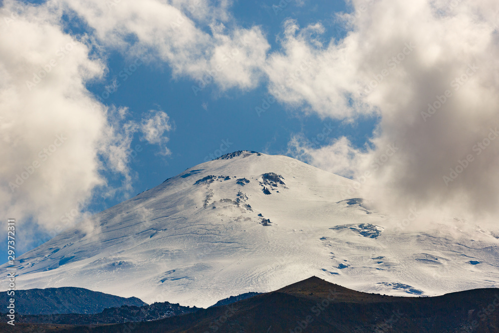 Sky with clouds over the snowy peak of Mount Elbrus, North Caucasus.