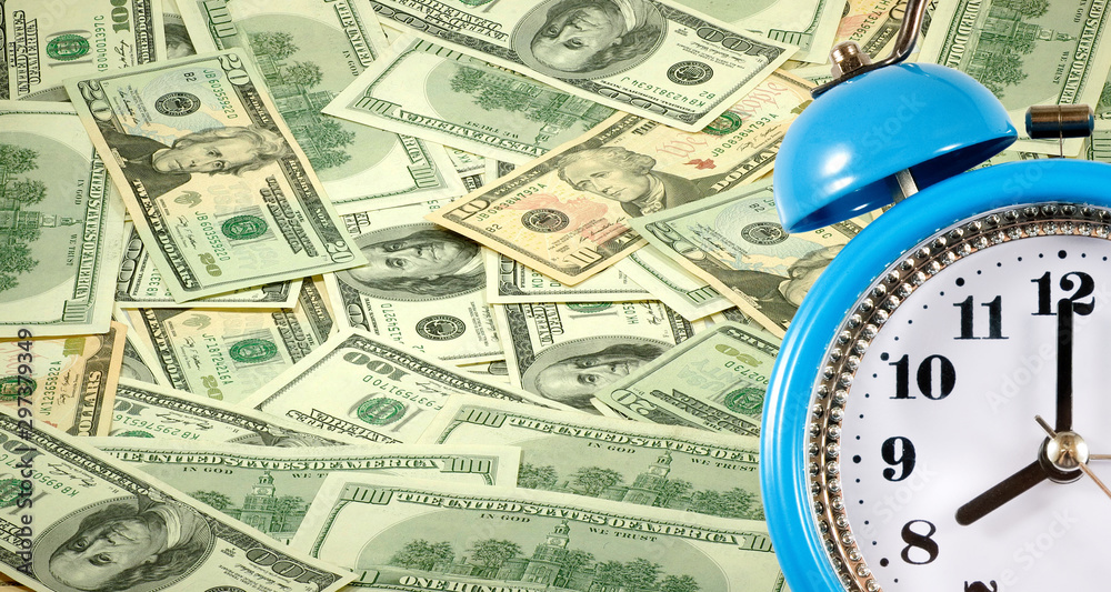 Alarm clock on a background of scattered dollar bills сloseup Alarm clock on a background of scattered dollar bills сloseup