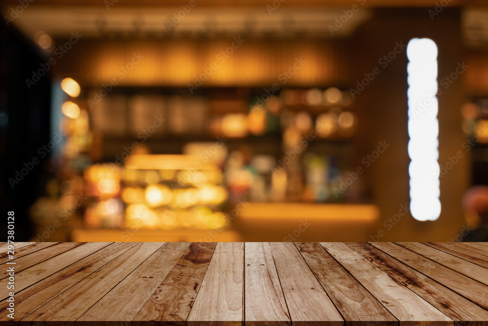 image of wooden table in front of abstract blurred background of coffee shop lights.Blur coffee shop or cafe restaurant with abstract bokeh light background.