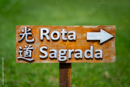 Placa de madeira sinalizando a direção da rota sagrada próxima ao templo japonês. Escrito em japonês e português photo