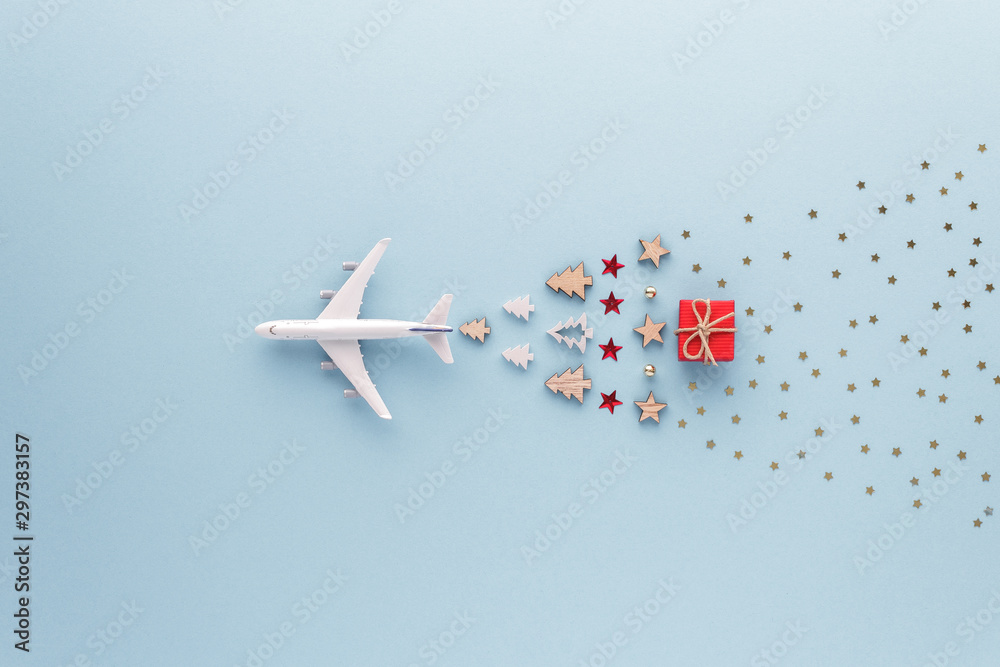 Fototapeta Christmas composition. Airplane flying in sky star gift bauble set top view background with copy space for your text. Flat lay.