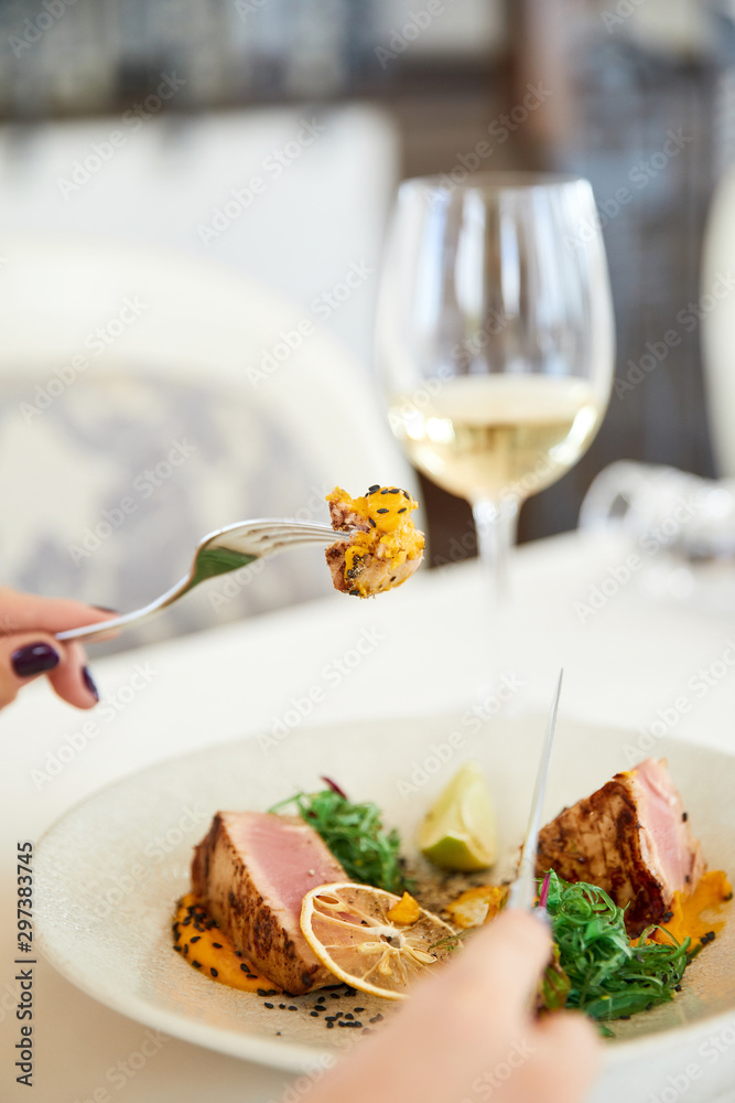 Slice of a tasty tuna meal with glass of white wine at the restaurant
