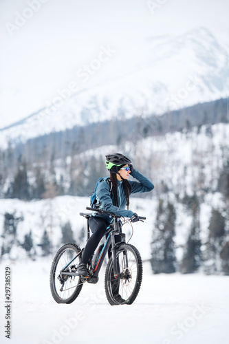 Female mountain biker standing on road outdoors in winter nature.